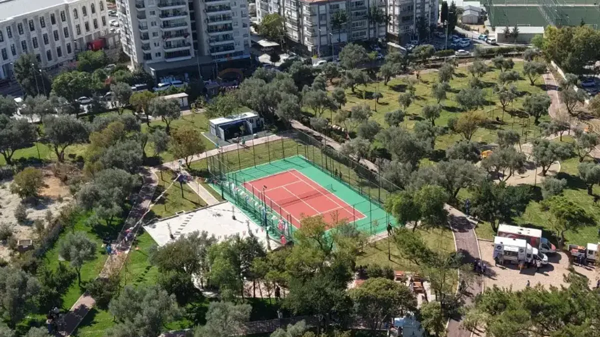 Buca Halk Park'ta kurulan açık hava spor istasyonunda modern aletlerle egzersiz yapan vatandaşlar ve spor eğitmenleri.